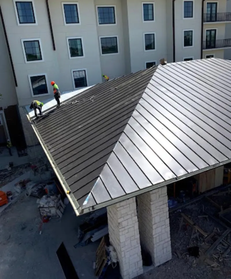 Crew installing standing seam metal roof panels on a commercial project in Lawndale